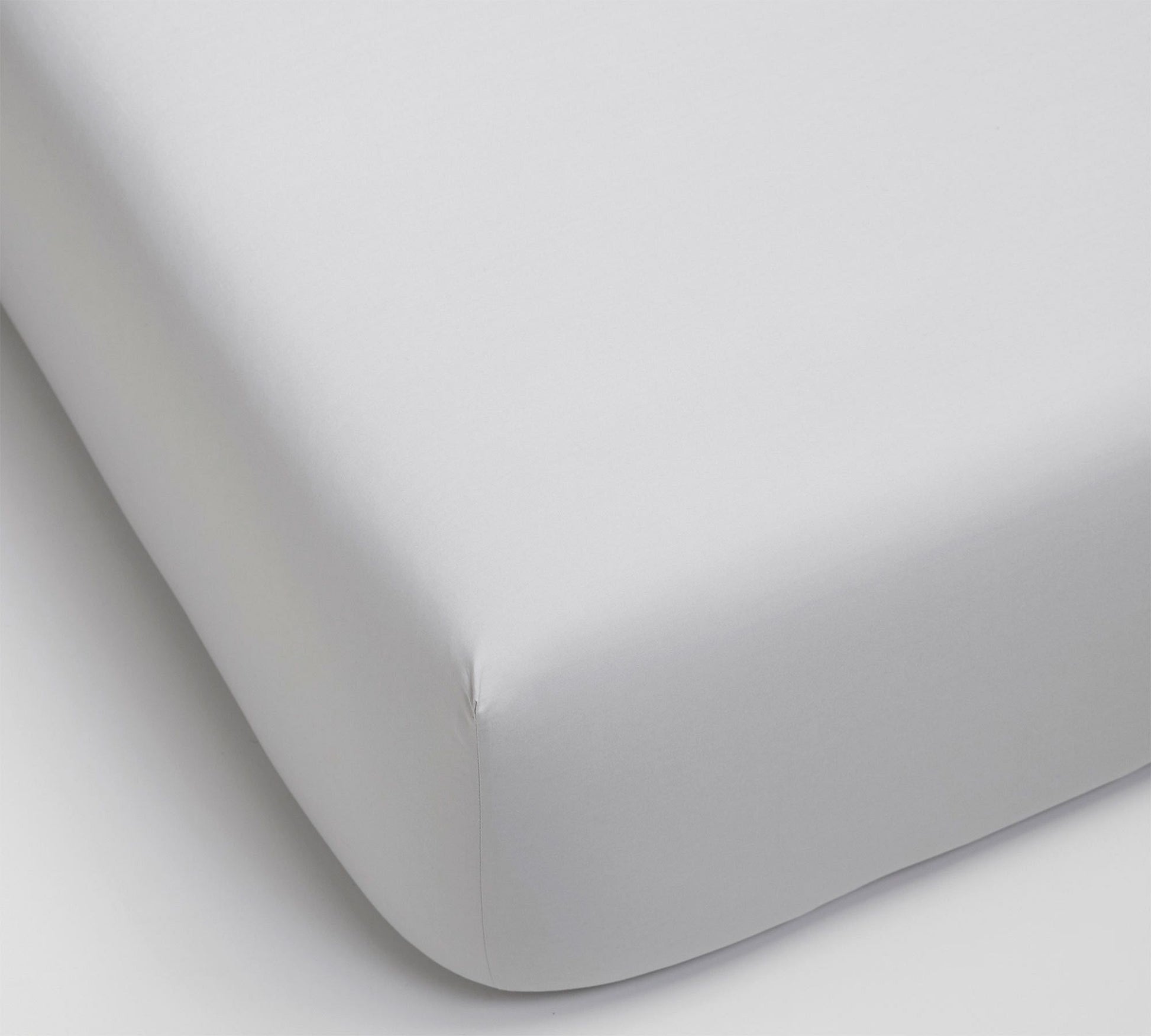 Close-up of a fitted sheet on a bed with a plain background